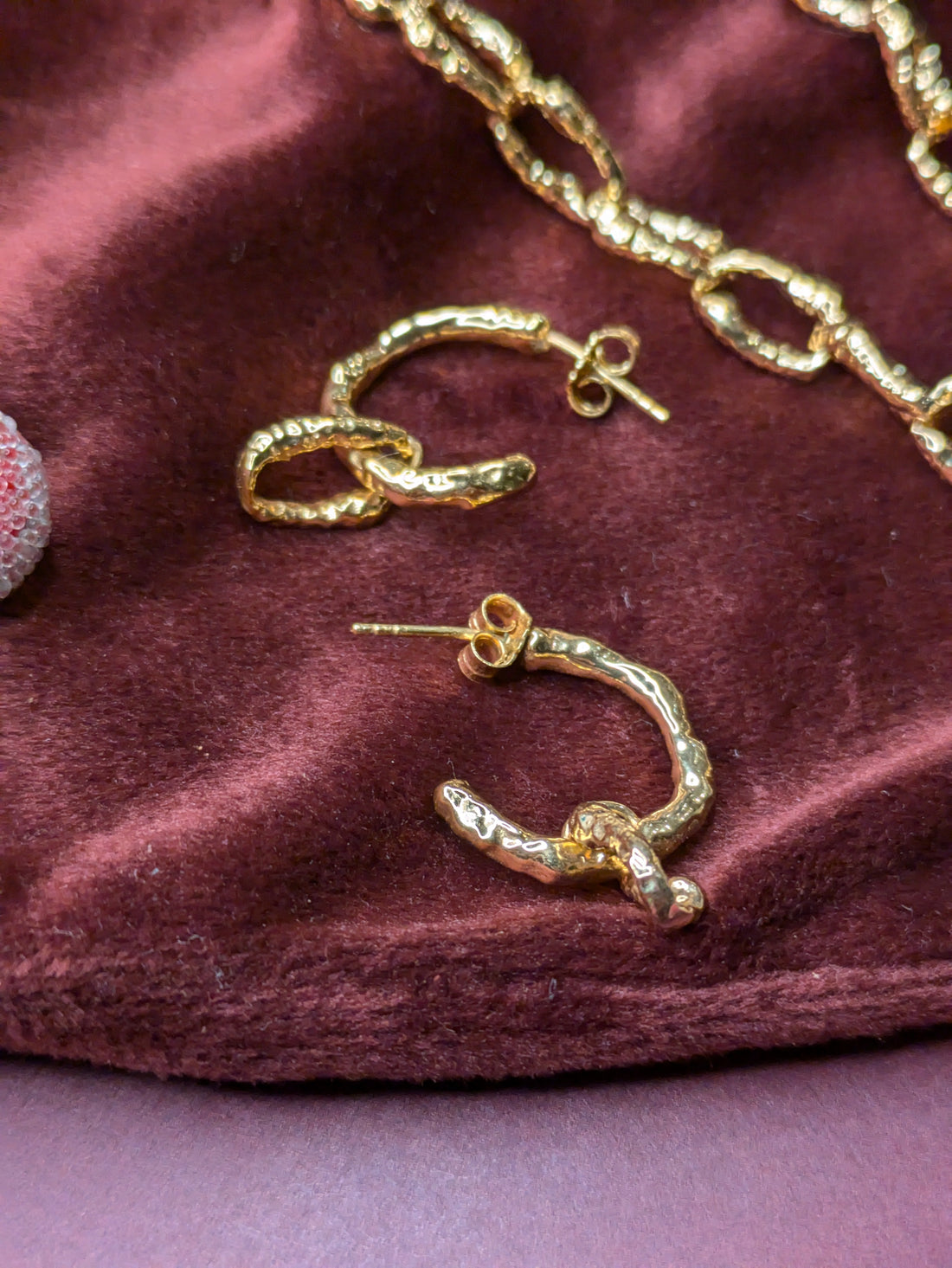 Another Mother hoop earrings on a burgundy felt cloth